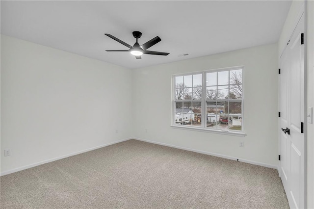 carpeted spare room with ceiling fan and baseboards