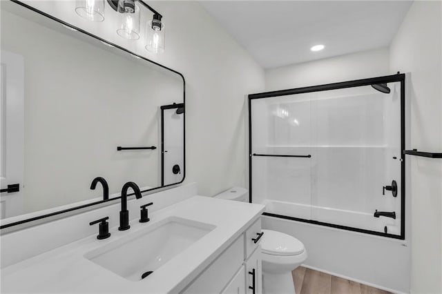 full bathroom featuring wood finished floors, toilet, vanity, and shower / bath combination with glass door