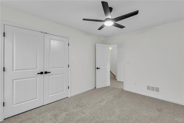 unfurnished bedroom with a closet, visible vents, light colored carpet, and baseboards