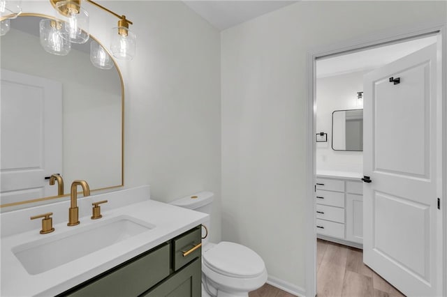 bathroom with toilet, vanity, and wood finished floors