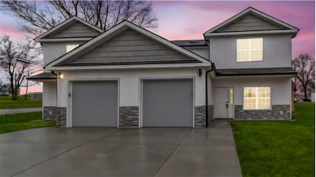view of front of property with a garage, stone siding, concrete driveway, and a front lawn