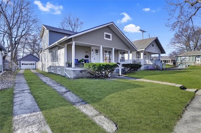 bungalow-style house with a front yard, covered porch, a garage, an outdoor structure, and driveway