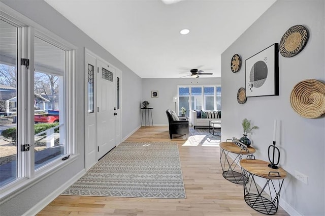 foyer entrance featuring light wood-style flooring, a ceiling fan, and baseboards