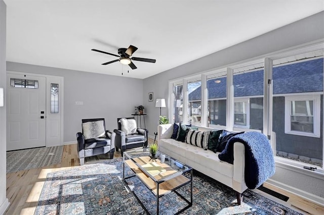 living room with ceiling fan, baseboards, and wood finished floors