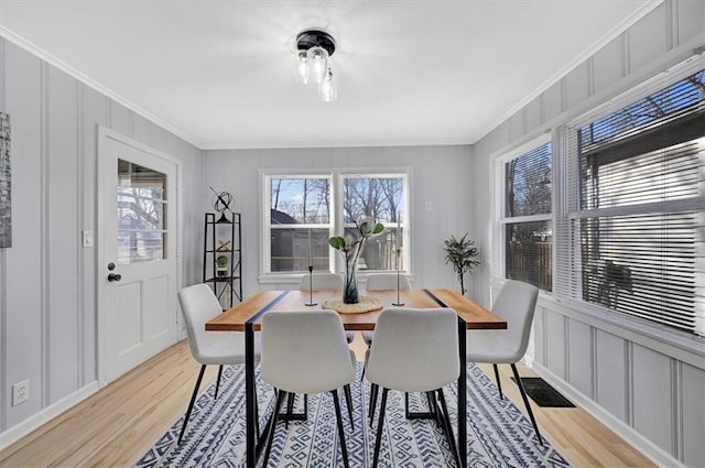 dining room with a wealth of natural light, crown molding, and a decorative wall