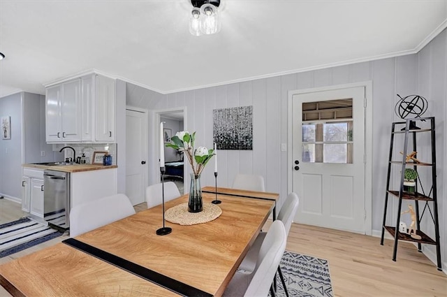 dining space with light wood-style floors and crown molding