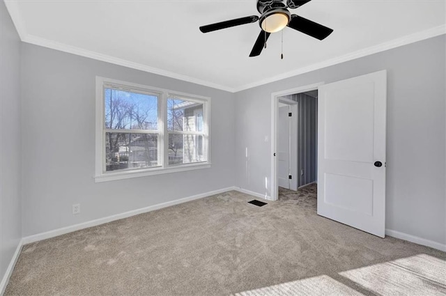 unfurnished bedroom with baseboards, a ceiling fan, ornamental molding, and carpet flooring