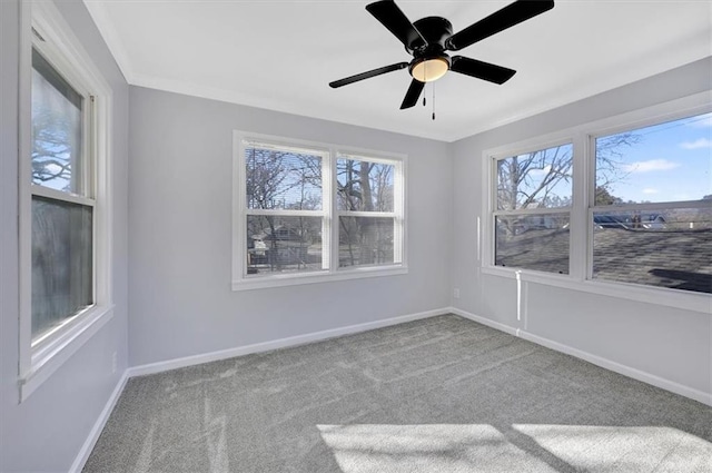 carpeted empty room with baseboards, ceiling fan, and crown molding