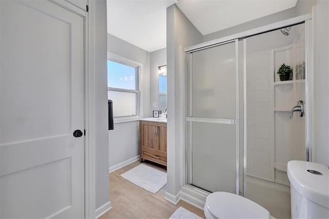 full bathroom featuring vanity, wood finished floors, baseboards, a stall shower, and toilet