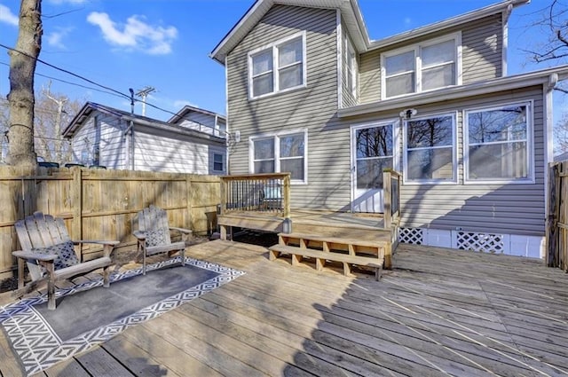 rear view of property with a deck, fence, and crawl space