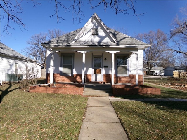 bungalow-style home with a shingled roof, a front yard, a porch, and brick siding