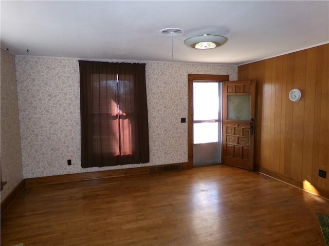 spare room featuring wood finished floors, baseboards, and wallpapered walls