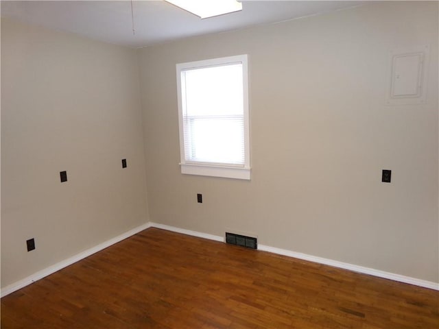 spare room featuring wood finished floors, visible vents, and baseboards