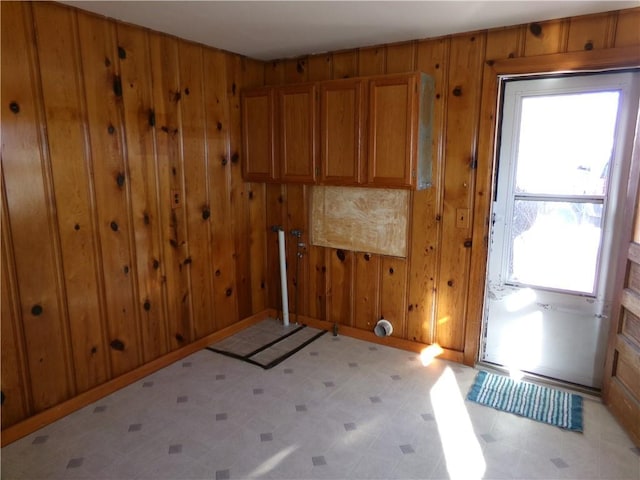 unfurnished room featuring light floors, wood walls, and baseboards