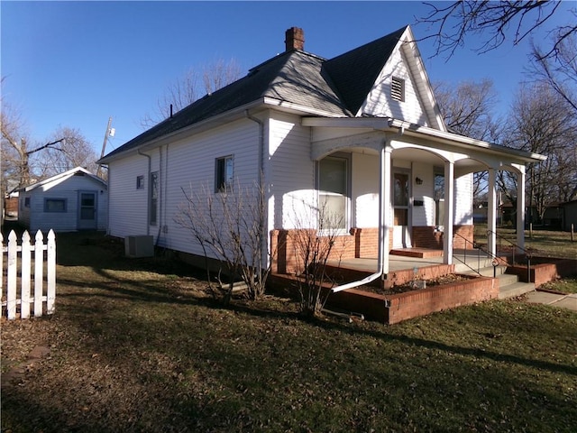 exterior space with covered porch, a chimney, fence, and a yard