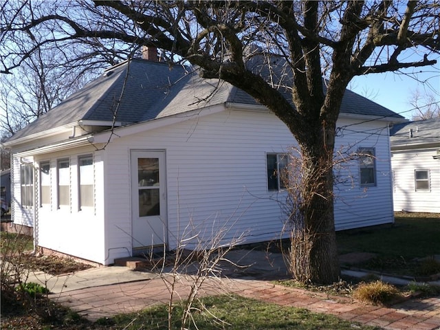 view of home's exterior with a shingled roof and a chimney