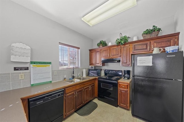 kitchen featuring light countertops, a sink, under cabinet range hood, and black appliances