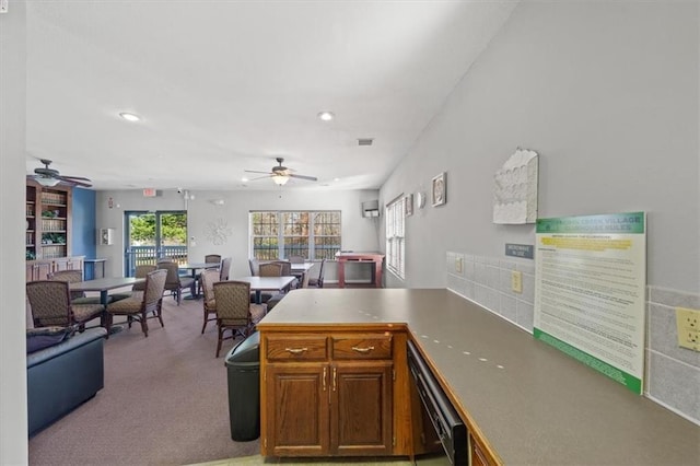 kitchen with a peninsula, ceiling fan, black dishwasher, and carpet flooring