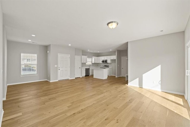 unfurnished living room with light wood-style floors, recessed lighting, and baseboards