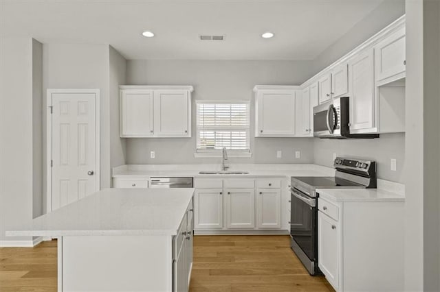 kitchen featuring visible vents, white cabinets, light wood-style flooring, appliances with stainless steel finishes, and a sink