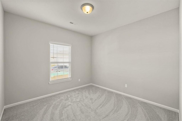 carpeted empty room featuring baseboards and visible vents