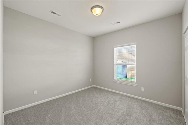 carpeted spare room with visible vents and baseboards