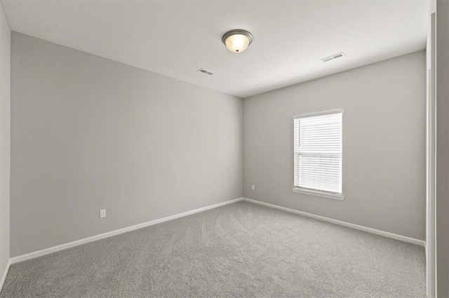 spare room featuring carpet, visible vents, and baseboards