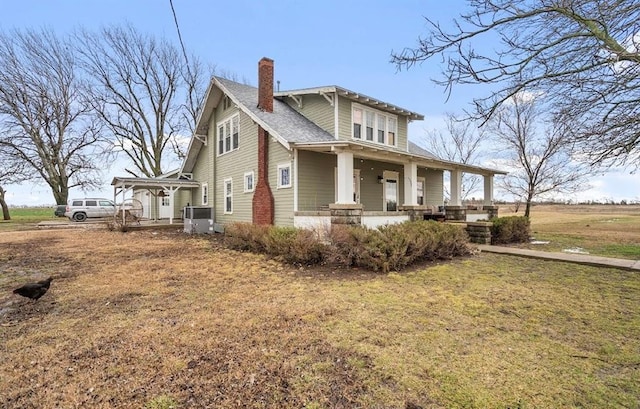 exterior space featuring covered porch, a chimney, and a front lawn