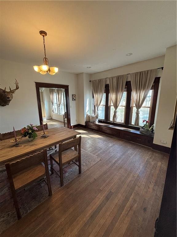 dining room with dark wood-style floors, plenty of natural light, a notable chandelier, and baseboards