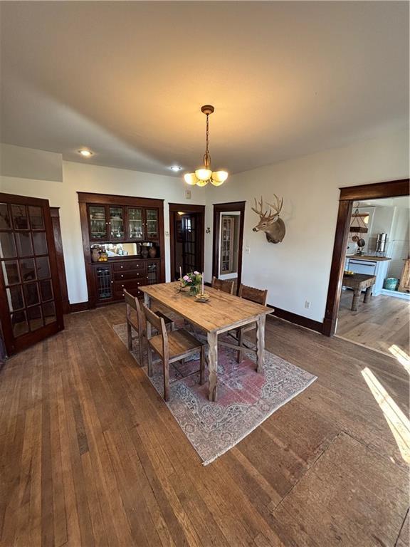 dining area featuring dark wood-style flooring, baseboards, and an inviting chandelier