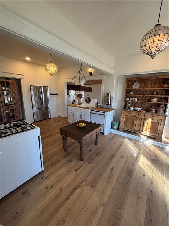 kitchen with white appliances, hardwood / wood-style floors, and decorative light fixtures