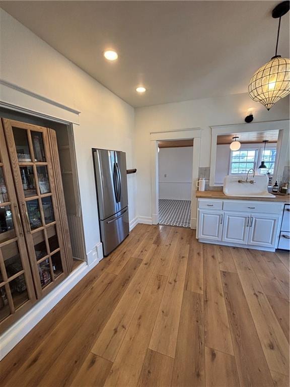 kitchen with decorative light fixtures, recessed lighting, light wood-style floors, freestanding refrigerator, and a sink