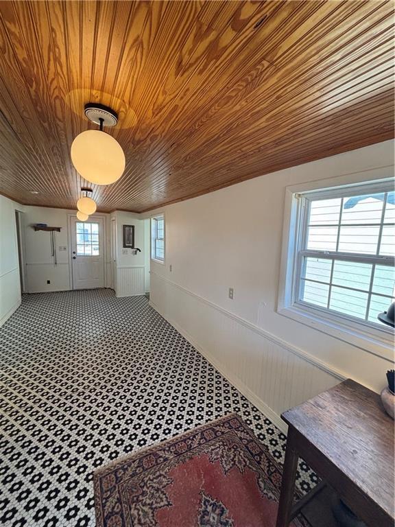 interior space featuring wood ceiling and a wainscoted wall