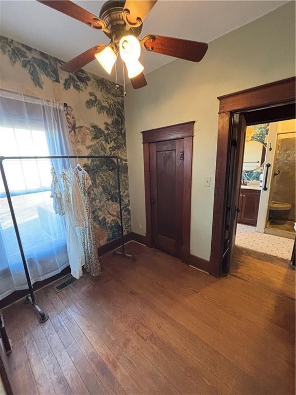 unfurnished bedroom with wood-type flooring, visible vents, baseboards, and a ceiling fan