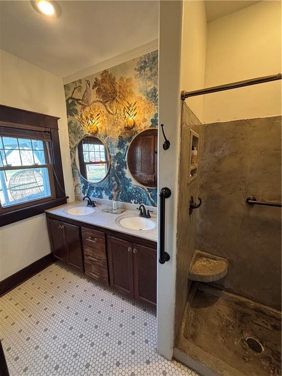 bathroom featuring double vanity, a sink, baseboards, and a walk in shower