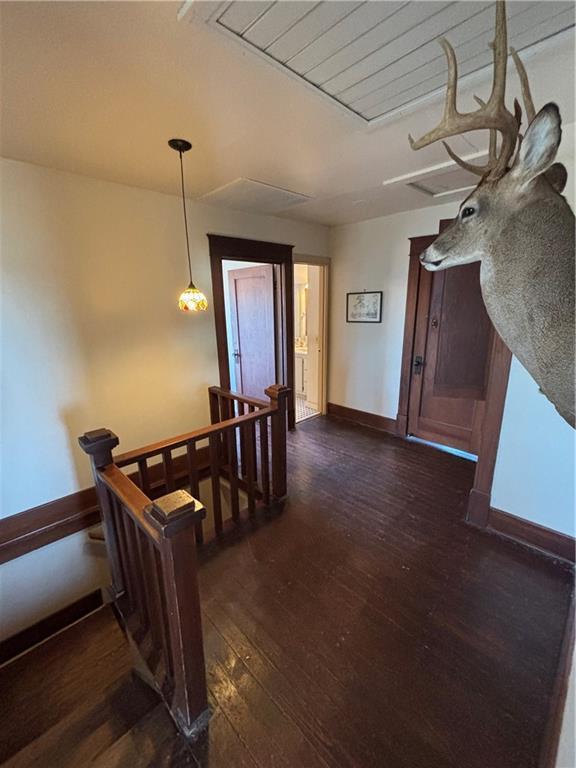 hall featuring baseboards, dark wood finished floors, and an upstairs landing