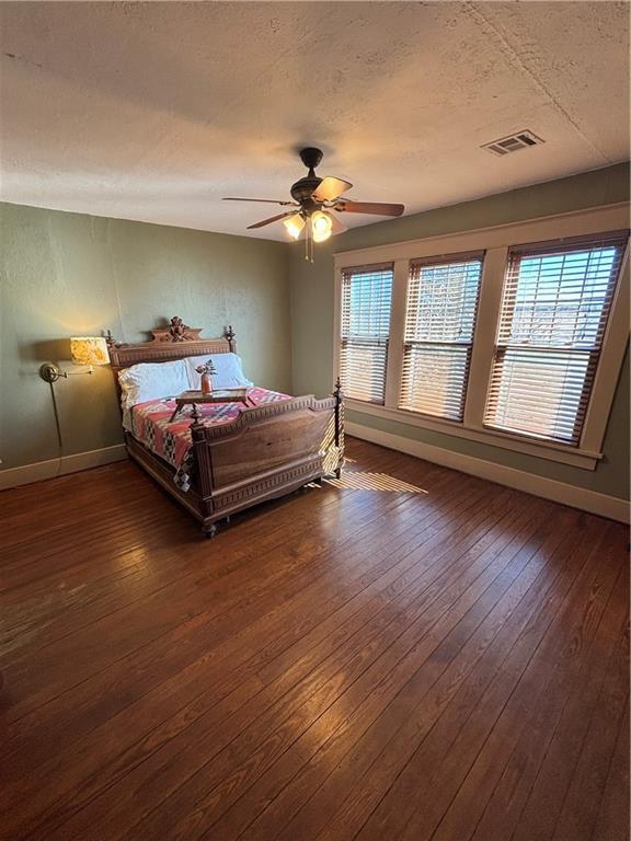 bedroom featuring dark wood-style floors, baseboards, visible vents, and a textured ceiling