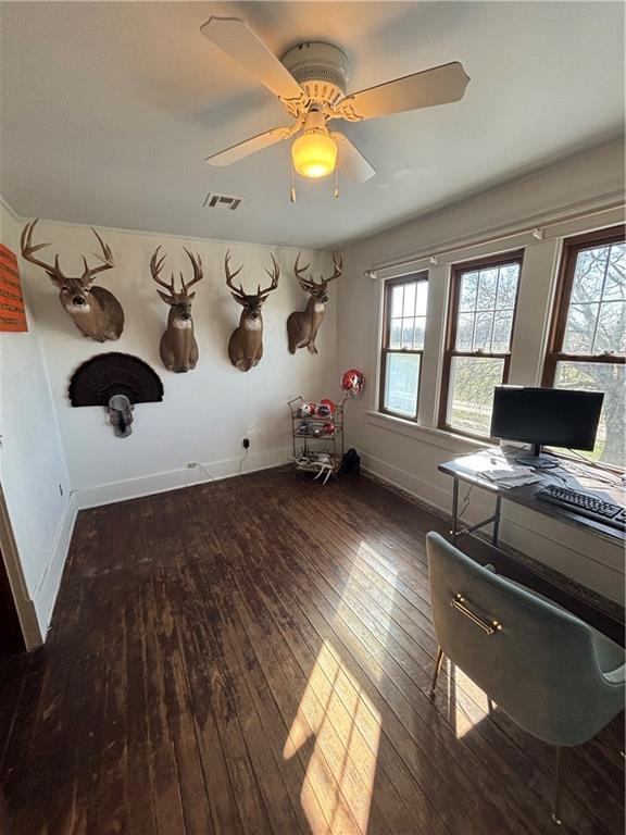 unfurnished office with hardwood / wood-style flooring, baseboards, visible vents, and ceiling fan