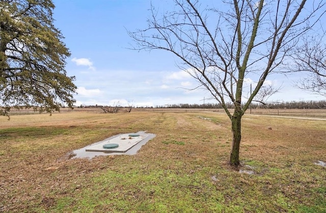 entry to storm shelter with a yard and a rural view