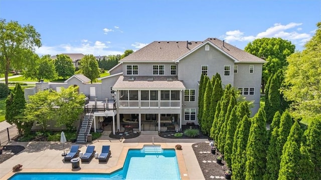 back of property with stairway, a sunroom, a patio, an outdoor pool, and fence