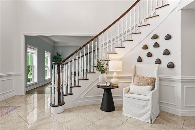 stairway with a decorative wall, a wainscoted wall, and crown molding