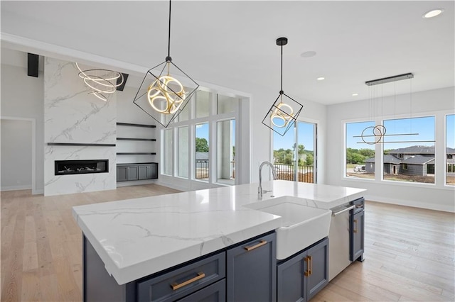 kitchen featuring light stone counters, open floor plan, light wood-style flooring, and a premium fireplace