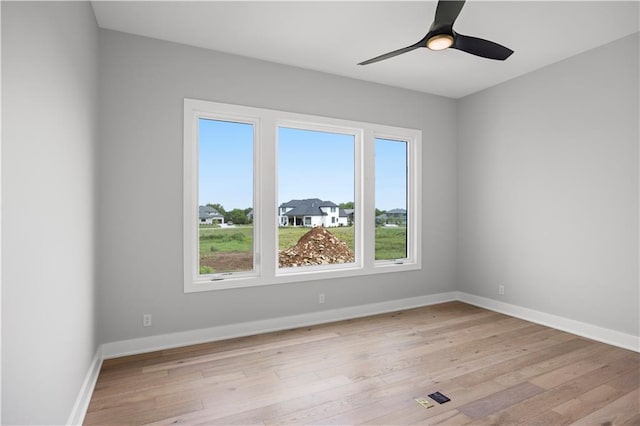 unfurnished room with light wood-type flooring, ceiling fan, and baseboards