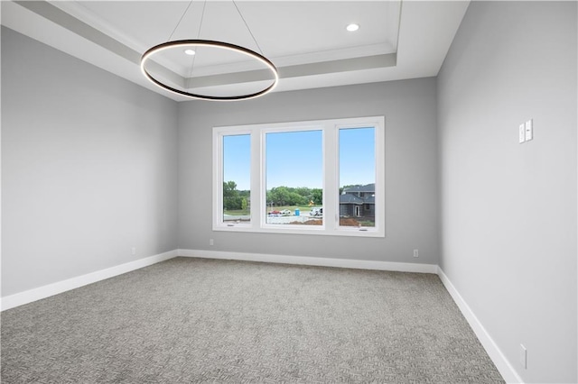 spare room with a tray ceiling, carpet, crown molding, recessed lighting, and baseboards