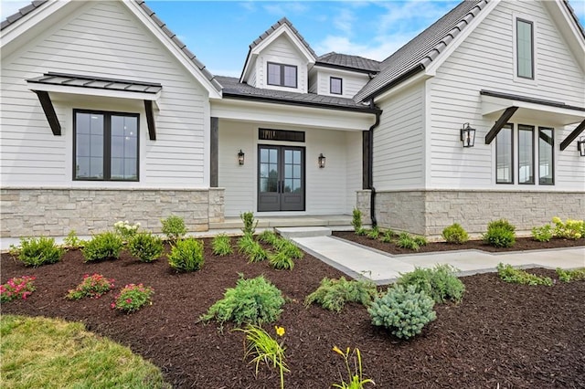 modern farmhouse featuring stone siding and french doors