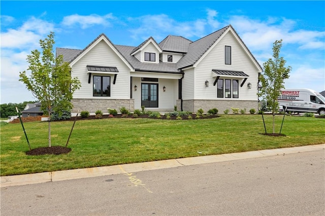 modern farmhouse style home featuring stone siding, french doors, and a front lawn