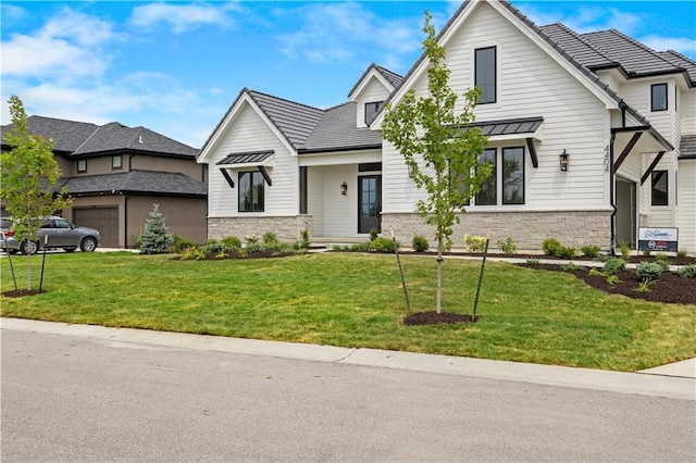 modern inspired farmhouse featuring stone siding, metal roof, a front lawn, and a standing seam roof