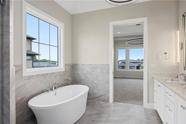 bathroom featuring a soaking tub, tile walls, a wealth of natural light, and vanity