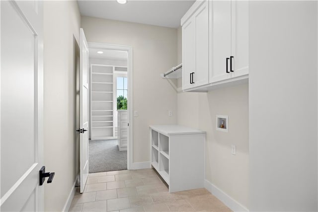 laundry area with washer hookup, light colored carpet, cabinet space, and baseboards