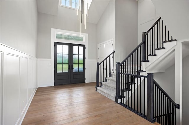 foyer featuring french doors, hardwood / wood-style flooring, a wealth of natural light, and a decorative wall